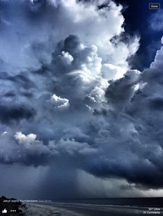 the sky is filled with dark clouds and some lightening in front of an ocean