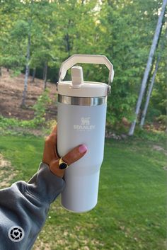 a woman holding up a white insulated water bottle