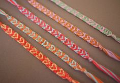 four different colored braided bracelets on a table