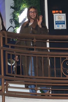 a woman standing on top of a balcony waving