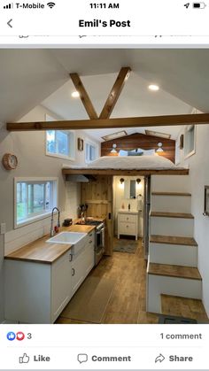 a kitchen and living room inside of a tiny house with stairs leading up to the loft