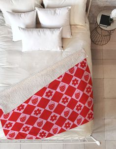 a red and white blanket on top of a bed in a bedroom next to pillows