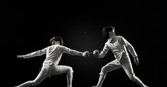 two people in white fencing suits are holding hands with each other while one person holds the string