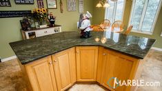 a kitchen with green granite counter tops and wooden cabinets, along with pictures on the wall