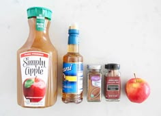 the ingredients to make an apple cider are displayed on a white surface, including apples and spices