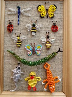 the beaded insect art is displayed in a wooden frame