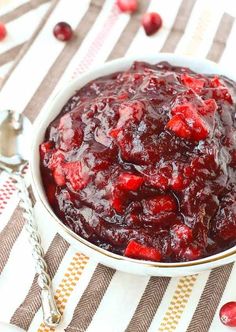 a white bowl filled with cranberry sauce on top of a striped table cloth