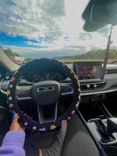 a person driving a car with flowers on the steering wheel