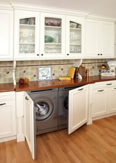 a kitchen with wooden floors and white cabinets, including a washer and dryer