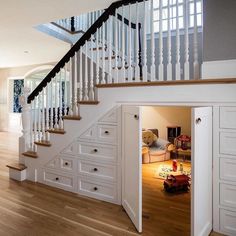 an open door leading to a living room with stairs and storage units in it,