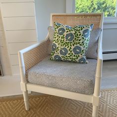 a white chair with blue and green pillows