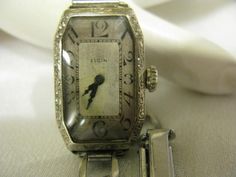 "Beautiful Rare solid white gold wrist watch, case has ornate design and little flowers all around, watch is working great for it's age, watch band is stainless steel and is adjustable from size 5.5\" to size 7\" wrist, the watch face is approx. 30mm. x 20mm. watch weighs 21 grams, hands are Black not blue. condition is great; If you have any question please ask prior bidding, Thanks watch face it's not stained and crystal is not cracked or damaged it only needs good cleaning because of the age. Antique Silver Diamond Watch, Antique White Gold Diamond Watch, Antique Silver Watch With Rectangular Dial, Antique Silver Watches With Rectangular Dial, Antique Silver Watch Accessories For Anniversary, Gold Wrist Watch, Elgin Watch, Ornate Design, 1920s Art