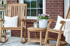 two wooden rocking chairs sitting on top of a porch next to a potted plant