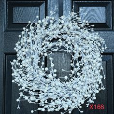 a wreath with white flowers is hanging on the front door, ready to be decorated for christmas