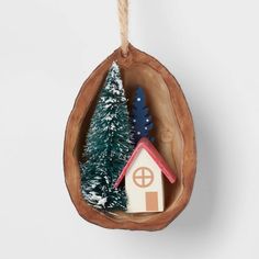 a small christmas tree in a hanging ornament with a house and trees inside