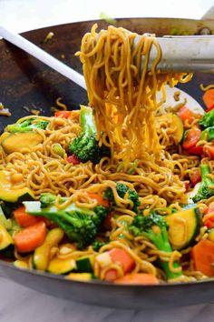 someone is eating noodles with vegetables in a wok