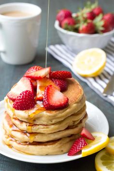 a stack of pancakes topped with strawberries and syrup