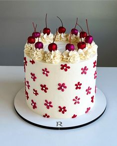 a white cake with red flowers and cherries on top is shown in an instagram