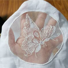 an embroidered butterfly on the back of a woman's white shirt with sheer lace