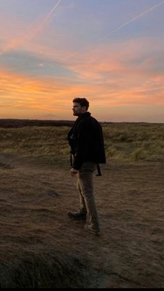 a man standing on top of a dirt field next to a bird flying in the sky