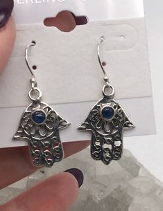 Kyanite Hamsa Hand Earrings The Hamsa hand and the Hand of Fatima are equally best known for the power to protect the owner from the evil eye and bring happiness to the holder. The holder of the Hamsa expects to be protected from all negative energies. The most common negative energy being envious glares from people wishing you no good.  925 Sterling Silver WWW.KARINSFORGOTTENTREASURES.COM Hand Earrings, Hand Of Fatima, Hamsa Hand, Bring Happiness, Jewelry Earrings Dangle, Etsy Earrings, Dangle Drop Earrings, Dangle Earrings, Jewelry Earrings