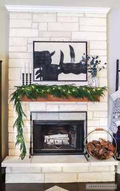 the fireplace is decorated with greenery and candles