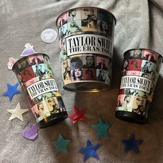 three tins with different pictures on them sitting next to stars and confetti