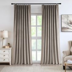 a living room with a chair and window covered in gray drapes, along with a white rug on the floor