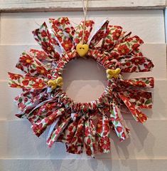 a wreath hanging on the side of a wall with ribbons around it and a bird