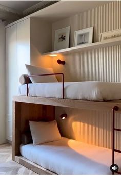 two bunk beds with white sheets and pillows in a room that has beige striped walls