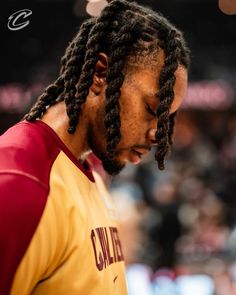 a close up of a person with dreadlocks in a basketball uniform looking down