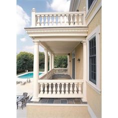 a house with a pool in the background and white balconies on either side