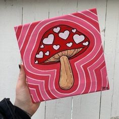 a person holding up a piece of art with hearts on it and a mushroom in the middle