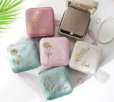 four personalized jewelry cases sitting on top of a white table next to a plant