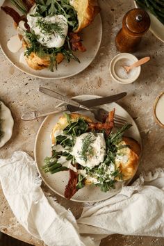 two white plates topped with food on top of a table next to utensils