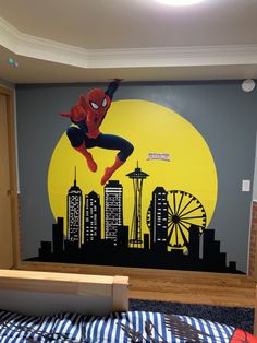 a child's bedroom with a spiderman mural on the wall and a bed