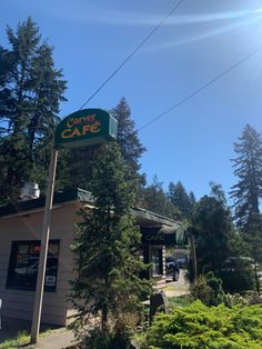 the outside of a cafe with trees and cars parked in front on a sunny day