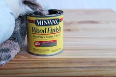 a can of wood finish sitting on top of a wooden table next to a stuffed animal