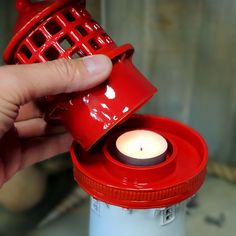 a person is holding a red tea light holder