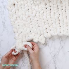 the crocheted blanket is being worked on by someone using their hands to knit it