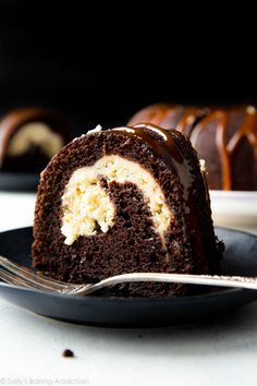 a piece of chocolate bundt cake on a black plate with a fork next to it