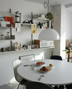 a white table with two plates of food on it in front of a shelf filled with shelves