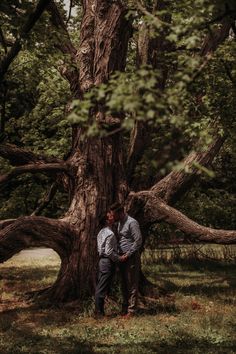 two people standing in front of a large tree