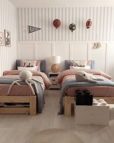 two beds in a room with striped walls and wooden floors, one has a stuffed animal on the bed