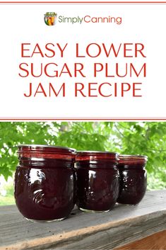 three jars filled with jam sitting on top of a wooden table in front of trees