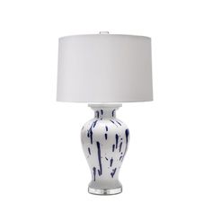 a white and blue vase lamp with a white shade on it's side, against a white background