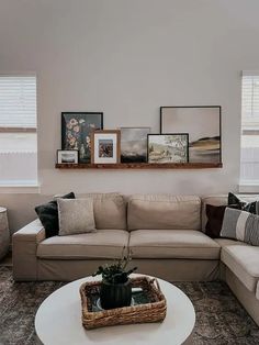 a living room filled with furniture and framed pictures on the wall over a white coffee table