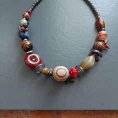 "Ready To Play. Funky mixed beads ^;^ Artsy assortment of swirled glass, tonal striped wood, and ceramic pottery. Lots of texture, shapes, sizes. Very 1970's Folk Art. Threaded on metallic wire. With shiny silver coils and frosted dangles. Festive to dress up or down. :) Lobster clasp and adjust chain. Total length: 22-1/2\" Gift boxed. 90's VINTAGE" Artsy Round Beads For Jewelry Making, Eclectic Wooden Beads Jewelry Gift, Eclectic Colorful Beaded Necklaces For Gifts, Eclectic Beaded Necklaces As Gift, Handmade Spiral Beaded Necklace As Gift, Spiral Multicolor Necklace Gift, Spiral Beaded Necklace As Gift, Spiral Beaded Necklace For Gift, Spiral Beaded Necklace For Gifts