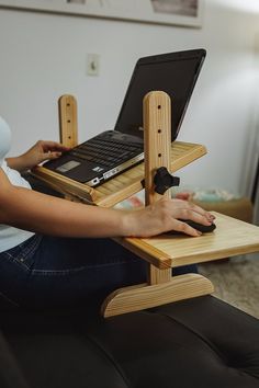 a woman sitting on a couch using a laptop computer stand with a mouse and keyboard attached to it