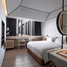 a hotel room with a bed, desk and mirror in the corner on the wall